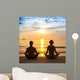 Young couple practicing yoga on sea beach. Wall Mural