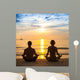 Young couple practicing yoga on sea beach. Wall Mural