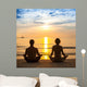 Young couple practicing yoga on sea beach. Wall Mural