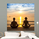 Young couple practicing yoga on sea beach. Wall Mural