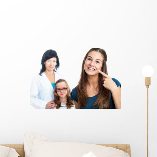 Teen girl pointing at dental barces with doctor in background. Wall Mural