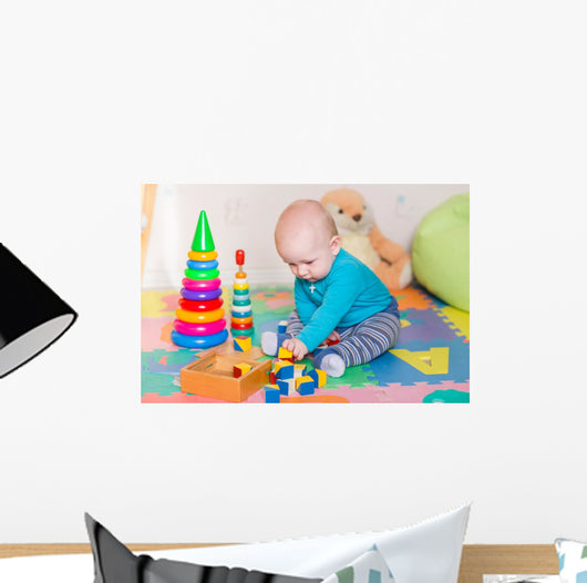 Cute little baby playing with colorful toys indoors Wall Mural