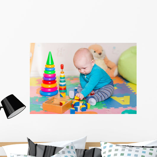 Cute little baby playing with colorful toys indoors Wall Mural