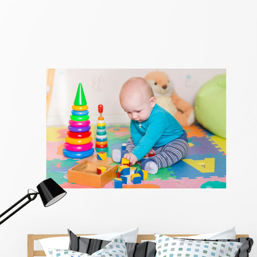 Cute little baby playing with colorful toys indoors Wall Mural