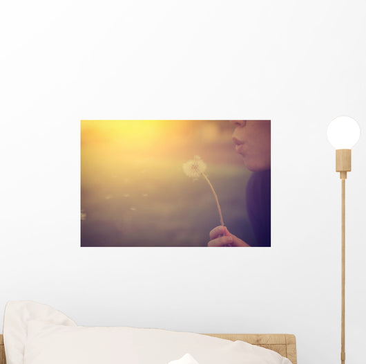 Woman blowing dandelion Wall Mural