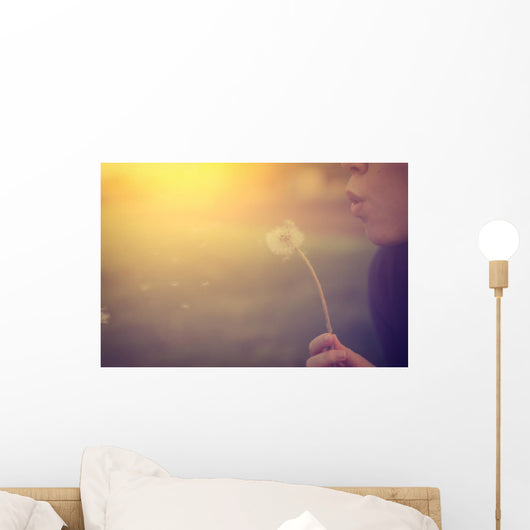 Woman blowing dandelion Wall Mural