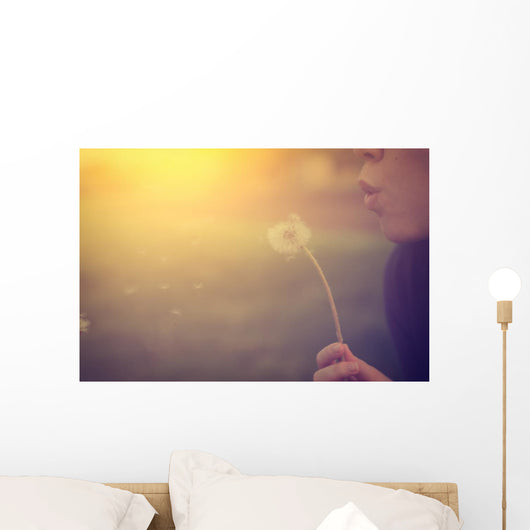 Woman blowing dandelion Wall Mural