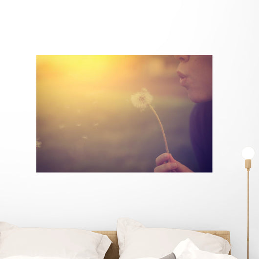 Woman blowing dandelion Wall Mural