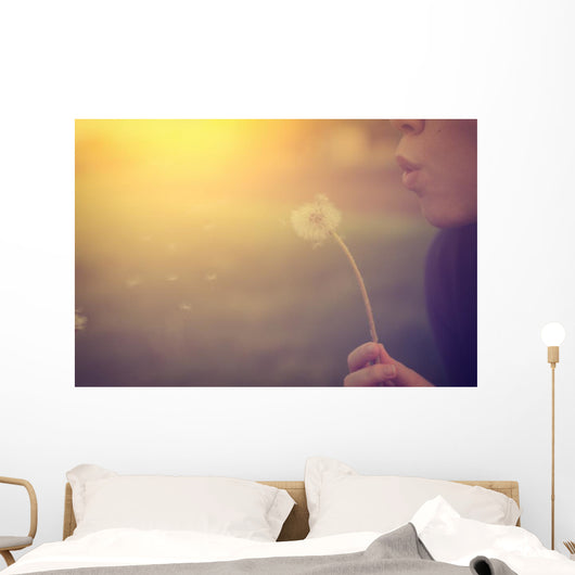 Woman blowing dandelion Wall Mural