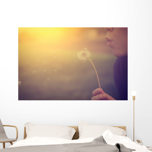 Woman blowing dandelion Wall Mural