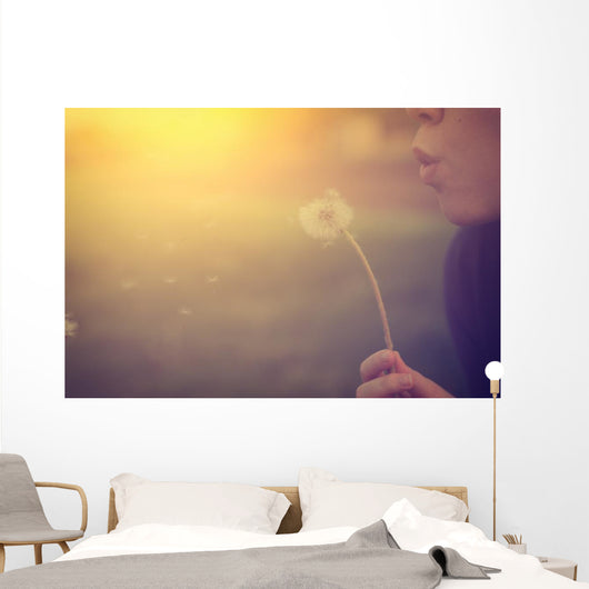 Woman blowing dandelion Wall Mural