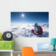 Hiker posing at top of snowy mountain during sunny day Wall Mural