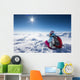 Hiker posing at top of snowy mountain during sunny day Wall Mural
