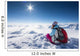Hiker posing at top of snowy mountain during sunny day Wall Mural