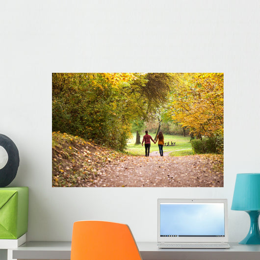Young love couple, holding hands walking in the autumn forest Wall Mural