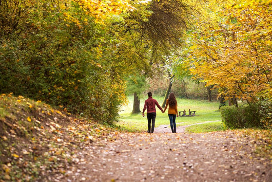 Young love couple, holding hands walking in the autumn forest Wall Mural