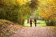 Young love couple, holding hands walking in the autumn forest Wall Mural