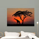 Silhouetted tree and giraffe against a red sunset Wall Mural