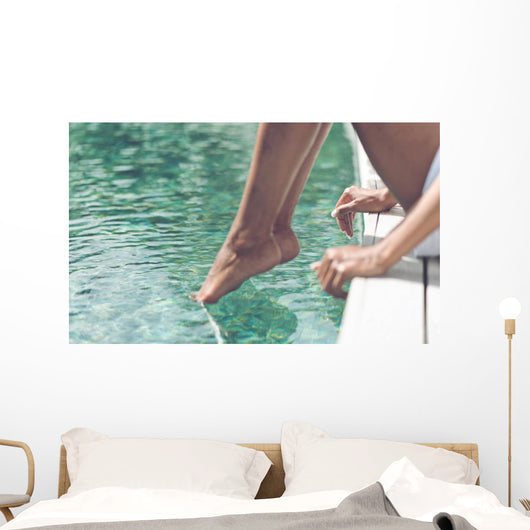 Young Woman Sitting at Poolside with Toes on Water Wall Mural
