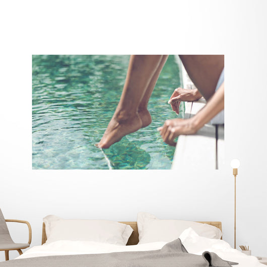 Young Woman Sitting at Poolside with Toes on Water Wall Mural