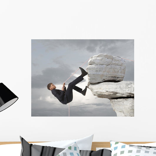Young businessman scaling a rock Wall Mural