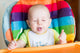 Adorable baby eating in high chair Wall Mural