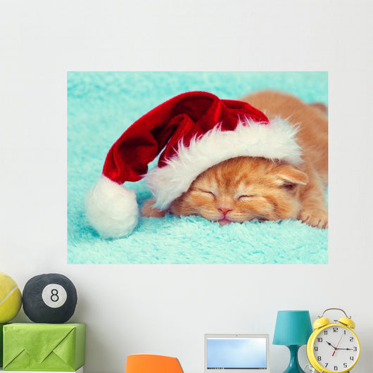 Little kitten wearing Santa's hat sleeping on a blue blanket Wall Mural