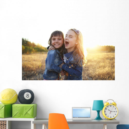 Two cheerful friends snuggling outdoors in the park Wall Mural
