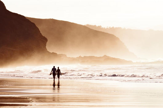 couple walking on beach with fog Wall Mural
