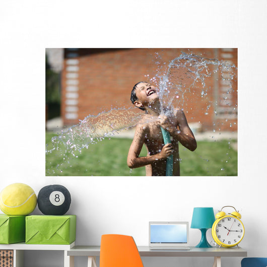 boy with splash water in hot summer day outdoors Wall Mural