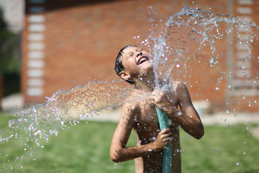 boy with splash water in hot summer day outdoors Wall Mural