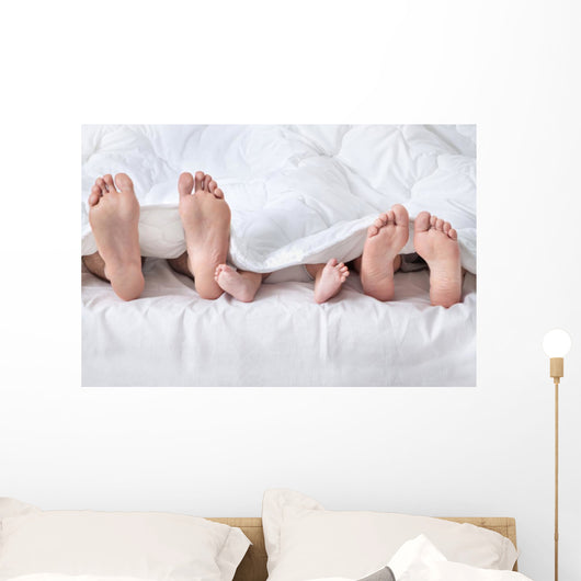 Feet of a family sticking out from the white quilt Wall Mural