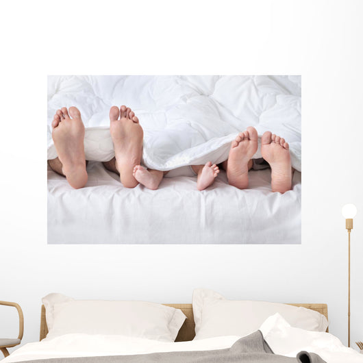 Feet of a family sticking out from the white quilt Wall Mural
