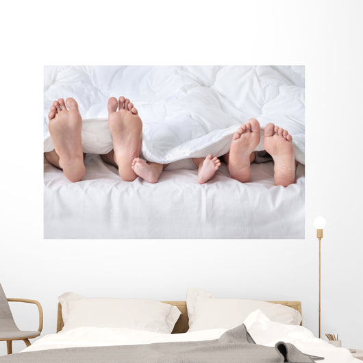 Feet of a family sticking out from the white quilt Wall Mural