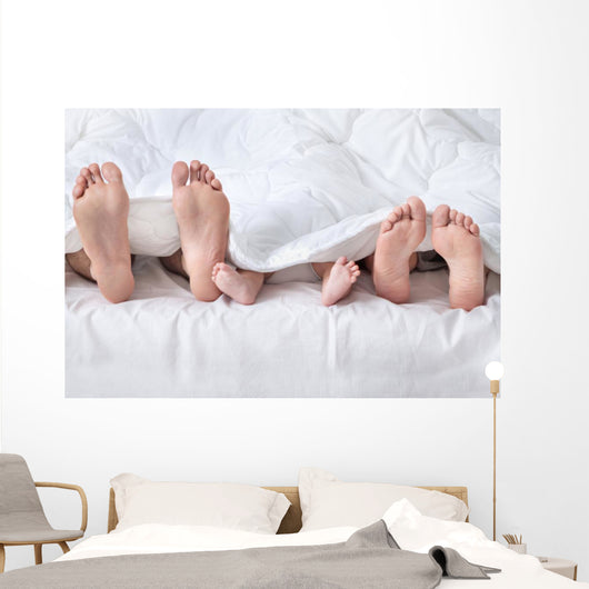 Feet of a family sticking out from the white quilt Wall Mural