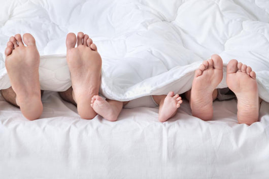 Feet of a family sticking out from the white quilt Wall Mural