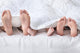 Feet of a family sticking out from the white quilt Wall Mural
