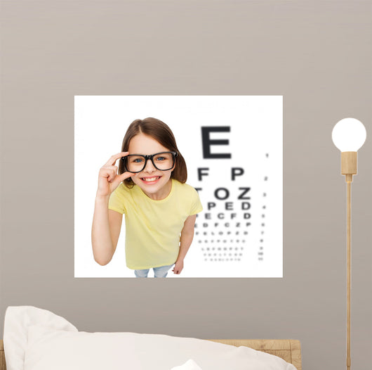 smiling little girl in eyeglasses with eye chart Wall Mural