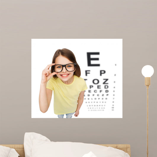 smiling little girl in eyeglasses with eye chart Wall Mural