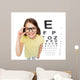 smiling little girl in eyeglasses with eye chart Wall Mural