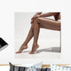 Beautiful woman tan legs. Against white wall. Wall Mural