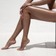 Beautiful woman tan legs. Against white wall. Wall Mural