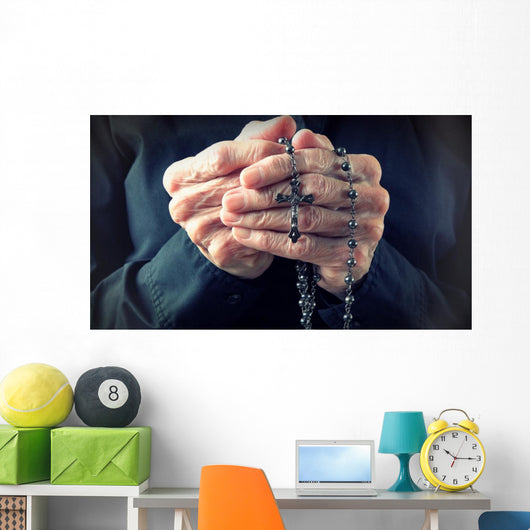 Hands of an elder woman holding a rosary while praying Wall Mural