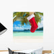Christmas sock on palm tree at exotic tropical beach Wall Mural