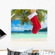 Christmas sock on palm tree at exotic tropical beach Wall Mural