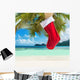 Christmas sock on palm tree at exotic tropical beach Wall Mural