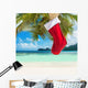 Christmas sock on palm tree at exotic tropical beach Wall Mural