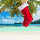 Christmas sock on palm tree at exotic tropical beach Wall Mural