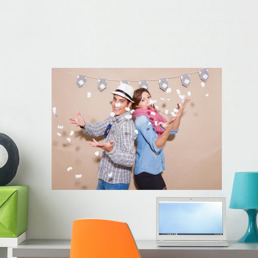 Young couple in a Photo Booth party with gesture face Wall Mural