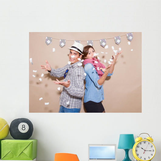 Young couple in a Photo Booth party with gesture face Wall Mural